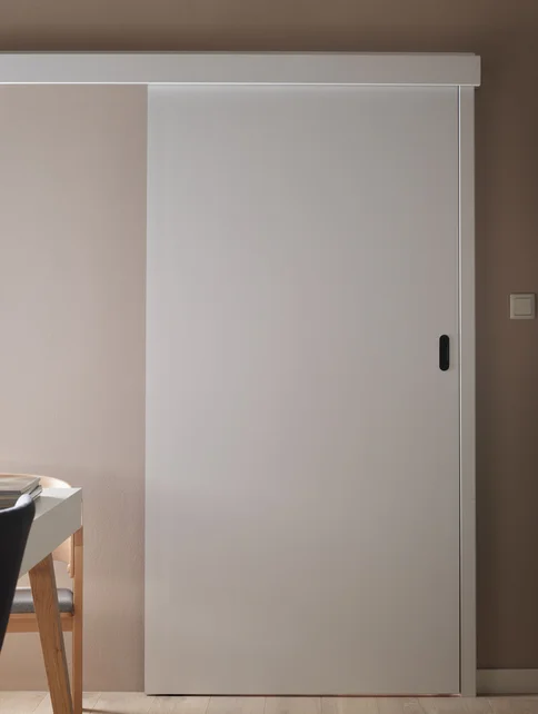 Proste białe drzwi przesuwne w minimalistycznym wnętrzu.